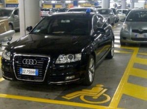 Un'auto blu sosta indisturbata sul parcheggio per disabili